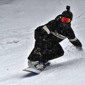 person in a black jacket and black pants riding on a snowboard