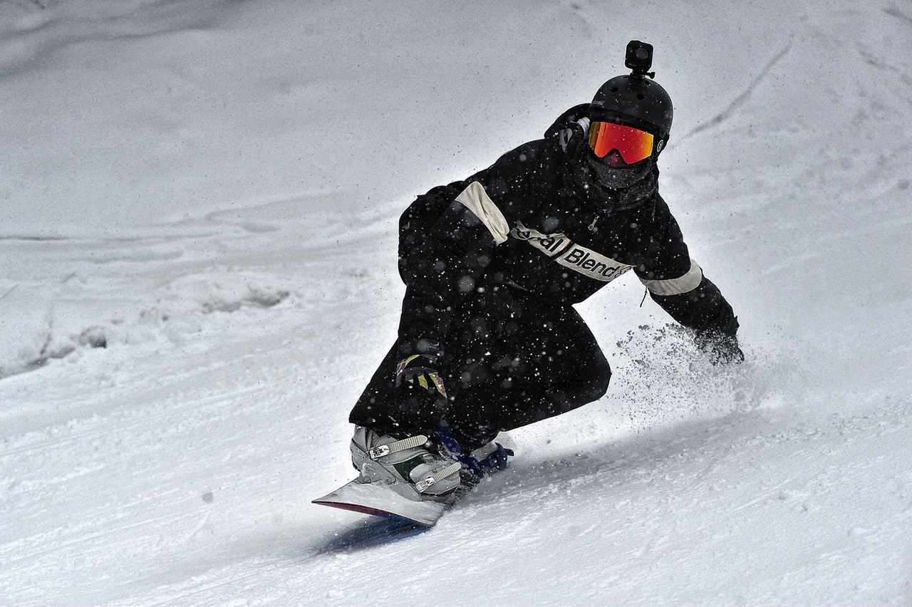 person in a black jacket and black pants riding on a snowboard